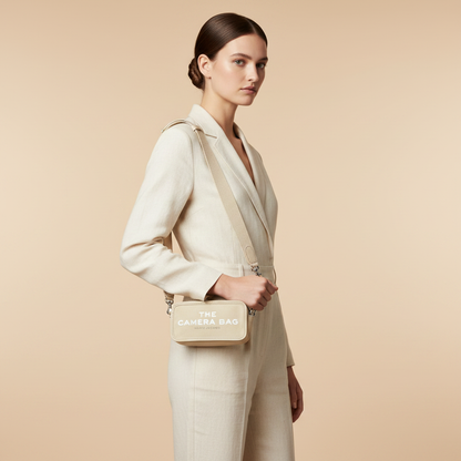 Marc Jacobs The Camera Bag Beige Canvas Crossbody Bag — held by model in studio