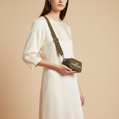 Marc Jacobs The Camera Bag Slate Green Canvas Crossbody Bag — held by model in studio
