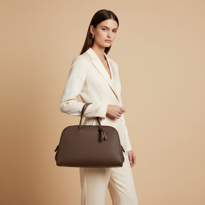 Jacquemus Le Grand Tourisme Brown Grained Leather Travel Bag — held by model in studio